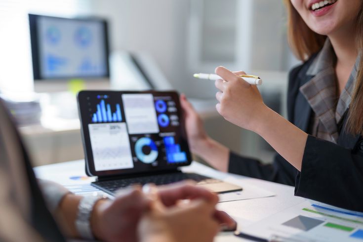 Advisor presenting financial scenarios and dashboards on a large screen to a business team